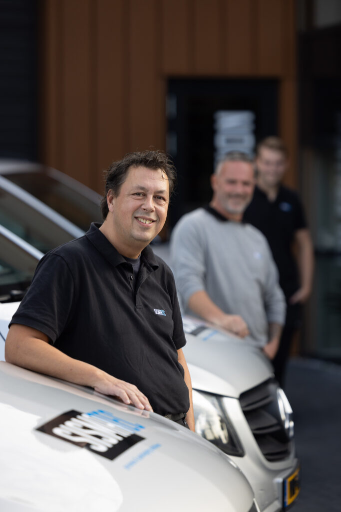 Vier Sismatec-servicemonteurs bij servicebussen voor onderhoud aan industriële verpakkingsmachines.