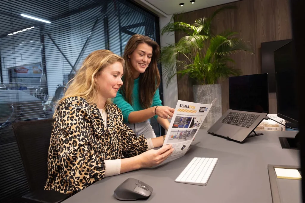 Twee Sismatec-medewerkers bespreken een Sismation-automatiseringsoplossing voor industriële verpakkingslijnen.