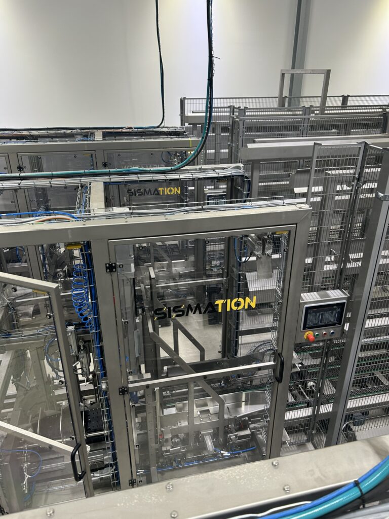 Automatische Sismation-krattenopzetter voor het ontstapelen en opzetten van kunststof kratten binnen een industriële verpakkingslijn.