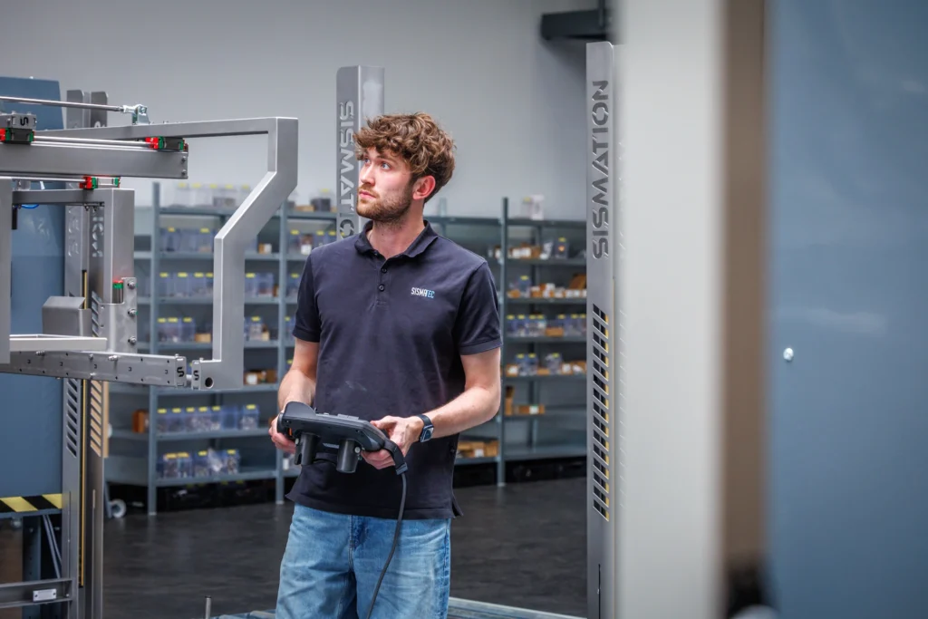 Sismatec-medewerker bedient een Sismation-automatiseringsmachine voor een industriële verpakkingslijn.