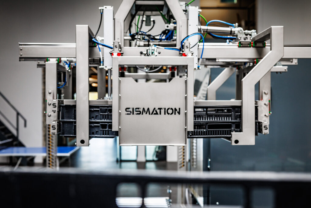 Sismation-automatiseringsmachine voor het automatisch verwerken van kunststof kratten binnen een verpakkingslijn.