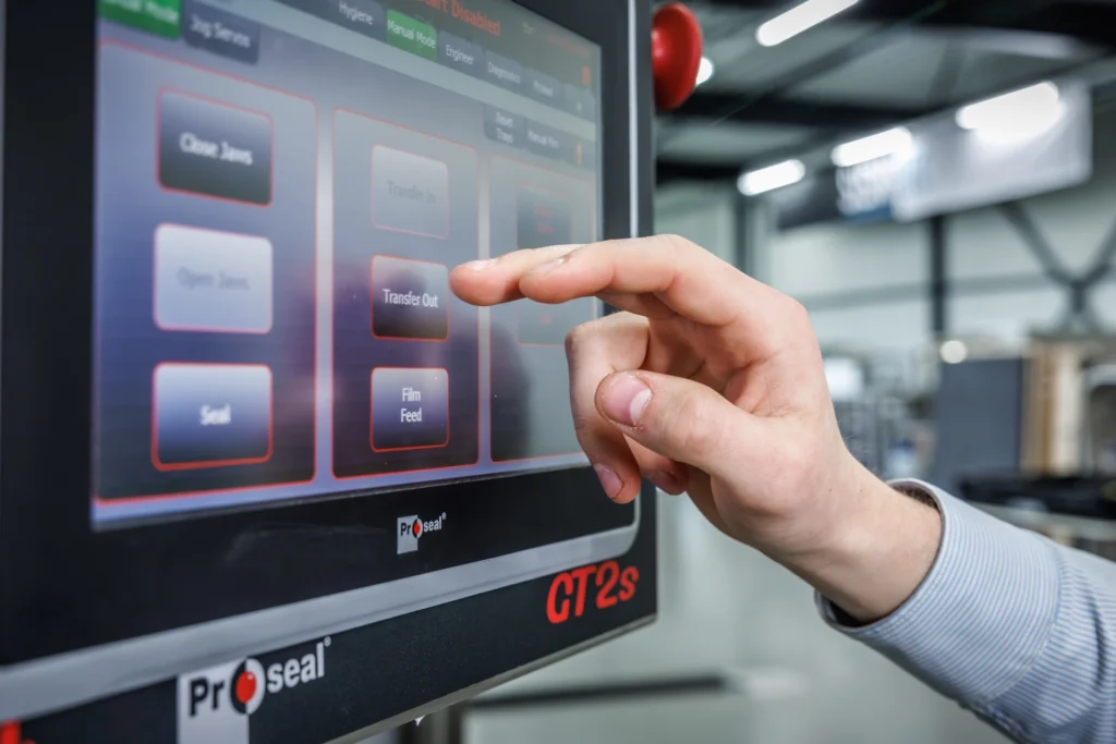 Medewerker bedient het touchscreen van een Proseal CT2s-traysealer voor het automatisch verpakken van voedingsmiddelen.