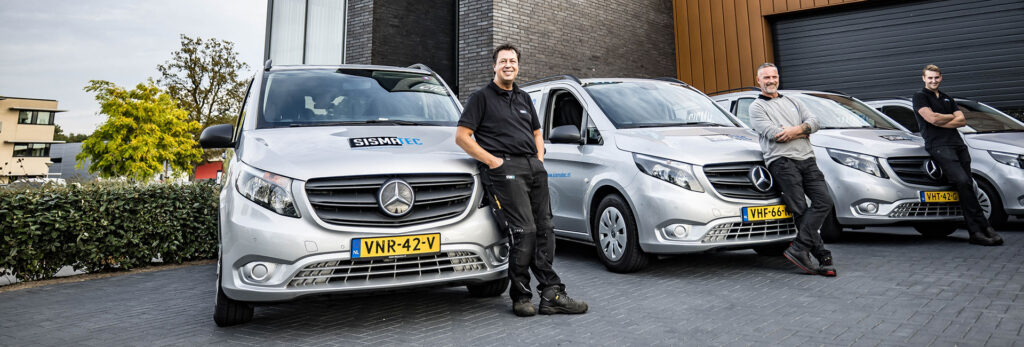 Vier Sismatec-servicemonteurs bij servicebussen voor onderhoud aan industriële verpakkingsmachines.